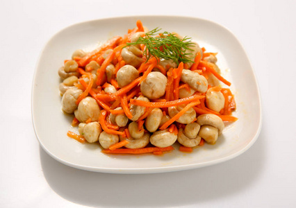 蘑菇用胡萝卜腌制在盘子里.照片