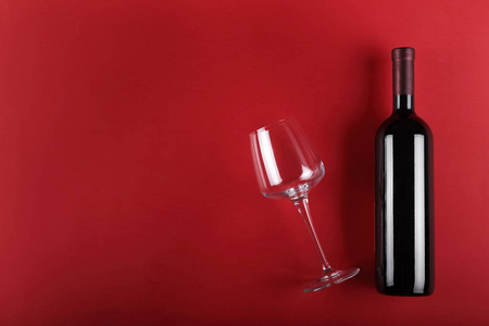 一瓶葡萄酒和一杯红色背景。 特克斯空间