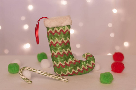 绿色长袜的手工礼物站在圣诞灯光的背景下，绿色糖果和球