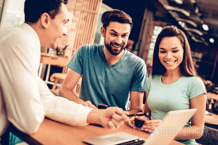 年轻幸福的夫妇咨询家具销售商. 客户和买家. 用笔记本电脑工作.