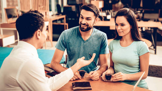 年轻幸福的夫妇咨询家具销售商. 客户和买家. 选择皮革颜色.