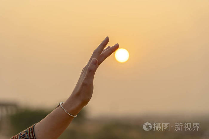 夕阳西下年轻女孩手捧太阳的剪影近在咫尺