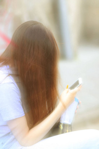 一个带着一张纸的年轻女孩，一杯咖啡坐在混凝土栅栏上，用手机说话。 电子通信的现代通信和技术。 阳光下的城市街道。