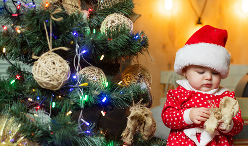 有趣的孩子婴儿与圣诞礼物。圣诞孩子们可爱的小宝宝正在室内装饰圣诞树。带着圣诞礼物的快乐婴儿