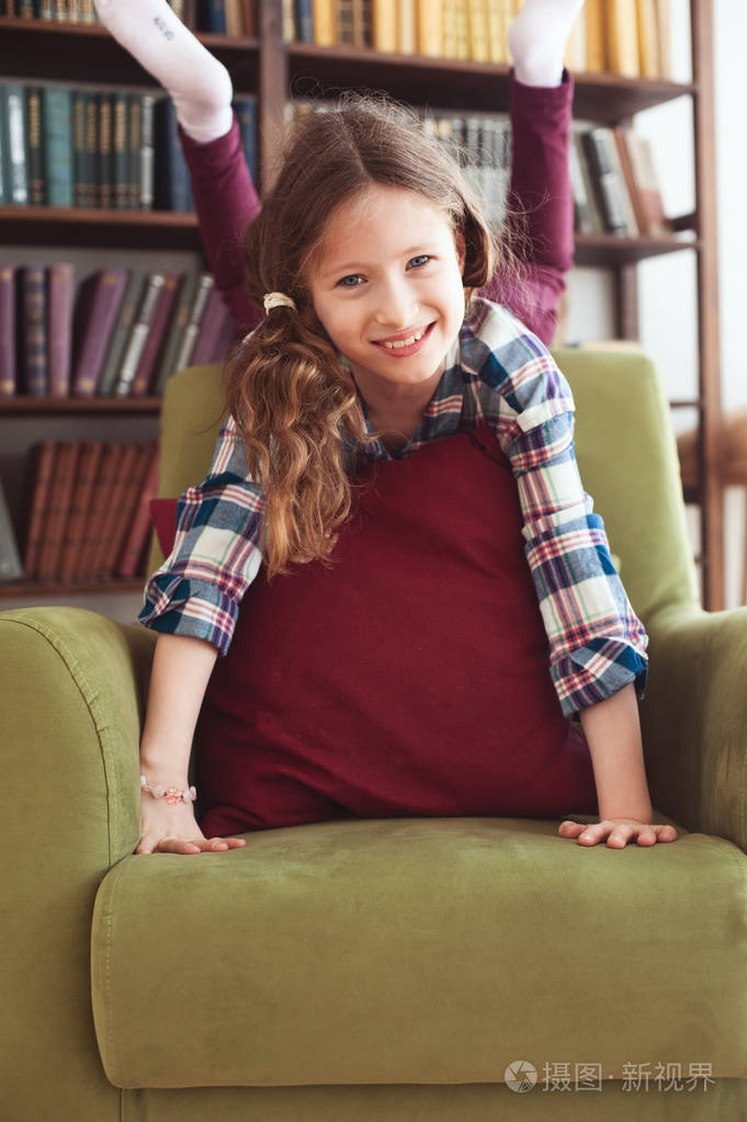 淘气有趣快乐的孩子女孩在家玩背景上有书架