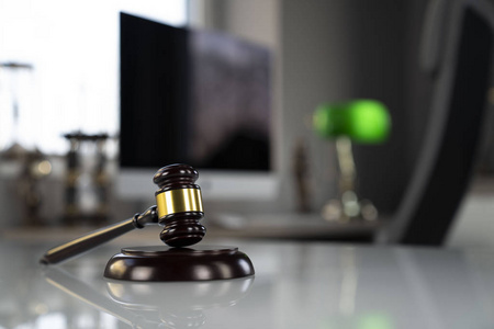 法律概念背景。 律师办公室白色玻璃桌子上的木槌和电脑。