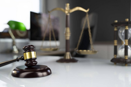 法律概念背景。 律师办公室白色玻璃桌子上的木槌和秤。