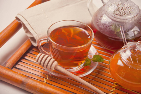 一杯热茶，茶壶和蜂蜜放在木盘上