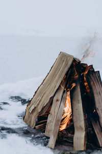 营火在冬季的时候，被雪包围在冰封湖的背景下..概念冒险活动度假户外徒步旅行