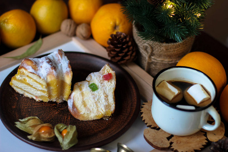 圣诞节装饰的景色。 圣诞物品干切片橙肉桂皮松果冷杉支杯咖啡芝士蛋糕胡桃金圣诞铃。
