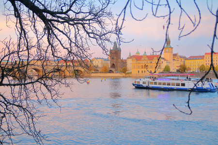 日落时在布拉格拍摄的照片。 这幅画显示了一艘船在伏尔塔瓦河上，背景是查尔斯桥和老镇。