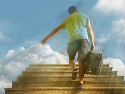 旅行箱人一个带着旅行箱的年轻人在阳光下跑上楼梯到天空.