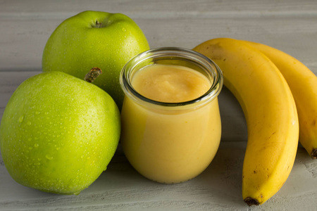 灰色的木制背景上有苹果和香蕉的果泥照片