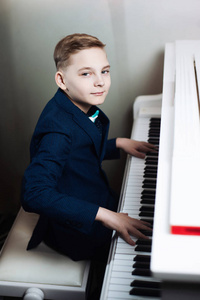 那个男孩弹钢琴。 时尚的孩子学会演奏乐器