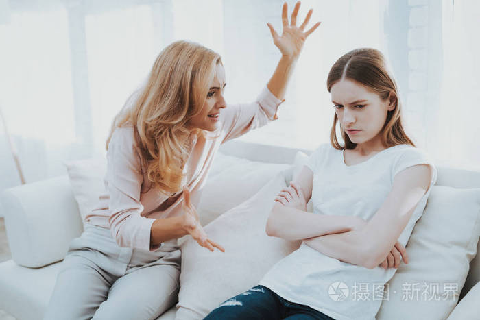 母女在白屋吵架情感的讨论坐在沙发上家庭冲突父母和孩子不开心的女孩