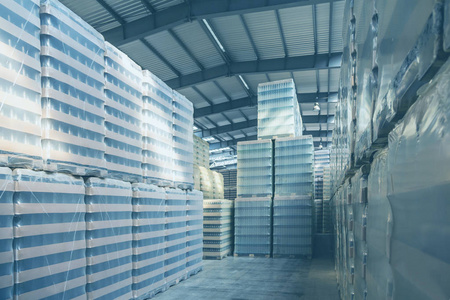 仓库里有包装好的玻璃瓶. 一排货架上有货物.照片