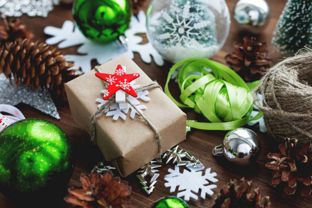 圣诞节和新年背景与礼物丝带球和不同的绿色装饰在木制背景。 礼品包装在工艺纸与红星。