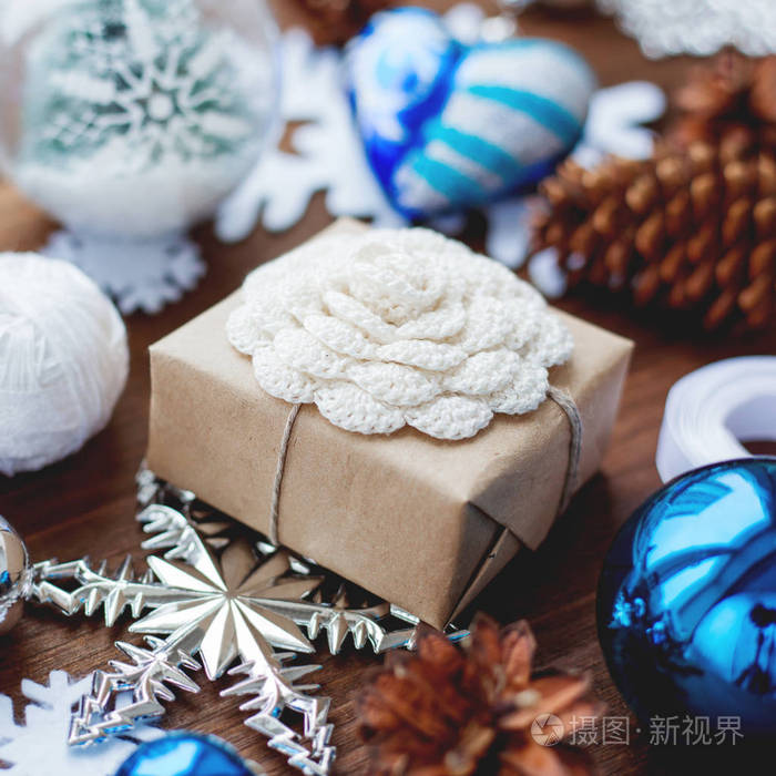 圣诞节和新年背景与礼物丝带球和不同的蓝色装饰在木制背景。 用手工制作的钩针花包装在工艺纸上的礼物。 DIY包装礼物的方式。