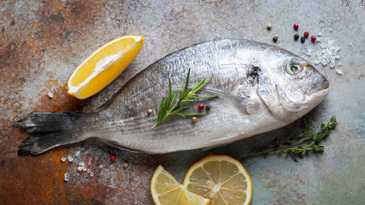 新鲜的生多拉多鱼与香料和橄榄油在蓝色生锈的桌子上。 上面的风景。 平躺着。