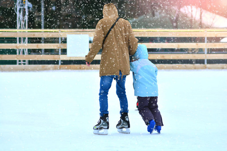 溜冰场。 父子在溜冰场上。 爸爸训练他儿子滑冰。 冬季运动。