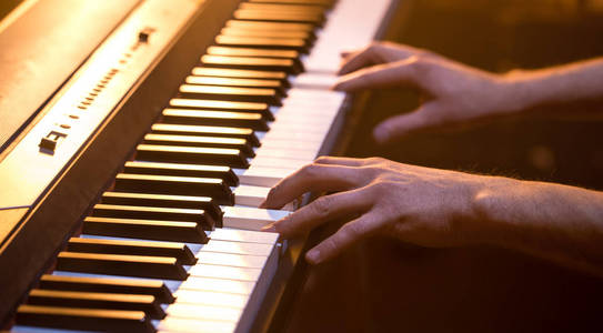 男手在钢琴琴键上特写一个美丽多彩的背景音乐活动的概念