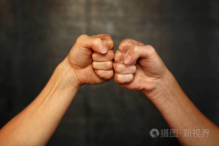 在拳击中,两个女人的手臂碰撞拳头打招呼手势在黑暗背景下,低角度侧视