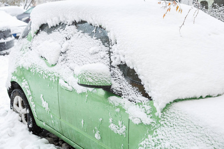 大雪天，雪覆盖了绿色的汽车。 驾驶安全概念。