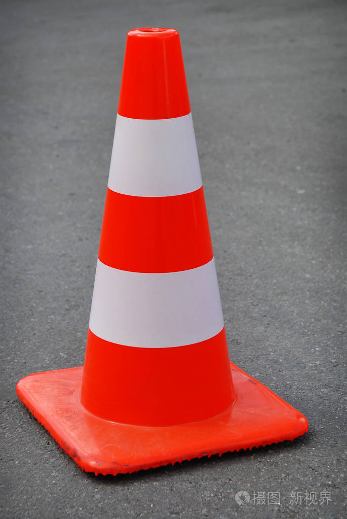 沥青路上有一个橙色和白色的交通锥