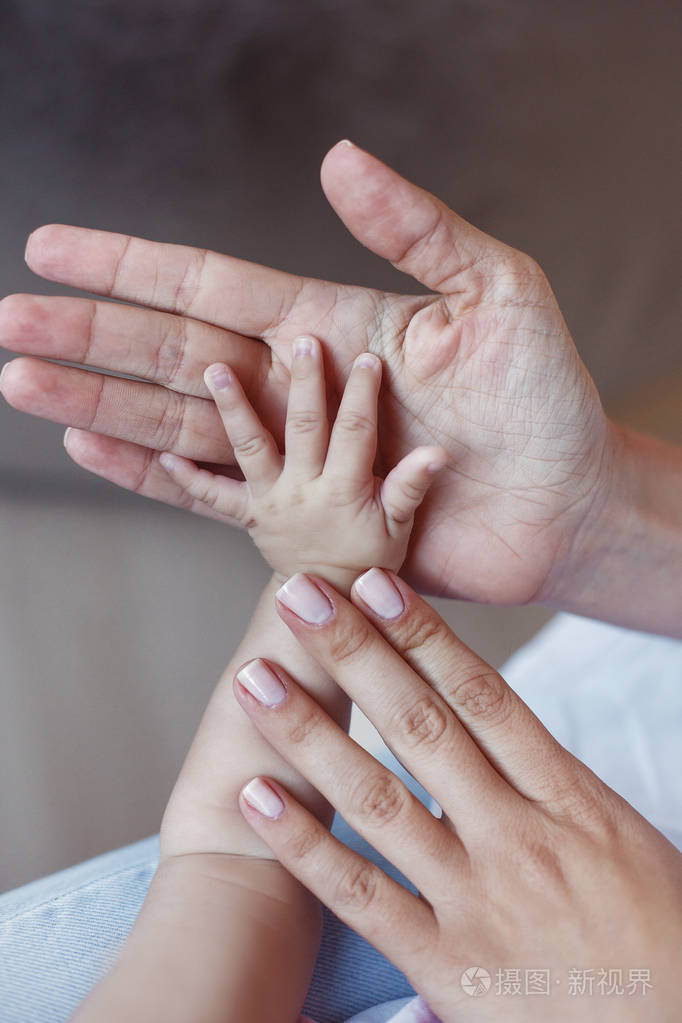 一个幸福的家庭的概念在父亲稚嫩的手掌上放着新生婴儿的手掌母亲轻轻