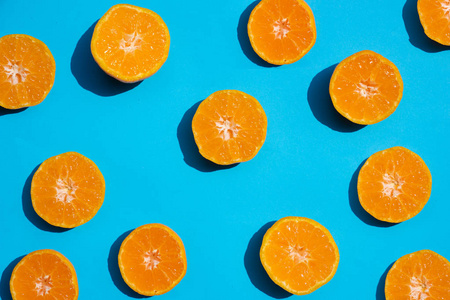 顶部查看新鲜橙色切片在明亮的蓝色背景。 。 复制空间。 创造性的夏季概念。 一半的柑橘在最小的旗帜
