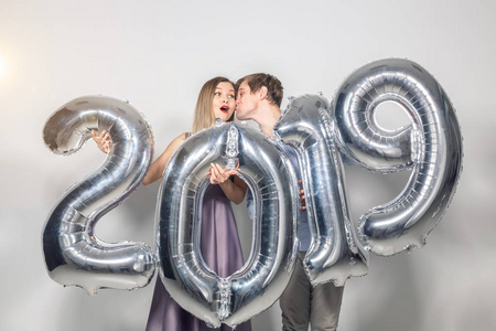 新年, 庆祝和节日概念有趣的爱情夫妇持有标志2019年由银气球制成的新的一年在白色背景