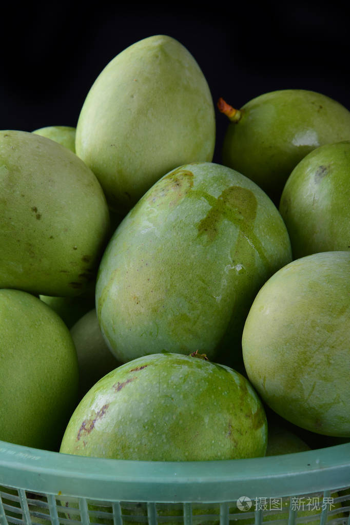 新鲜的绿色芒果在黑色背景的篮子里照片-正版商用图片15w7p8-摄图新视