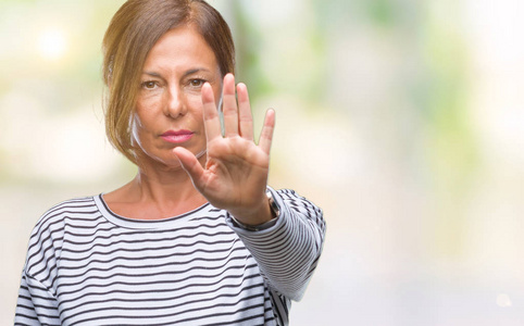 中年老年西班牙裔妇女在孤立的背景下做停止用手掌唱歌。 警告表情，脸上有负面和严肃的手势。