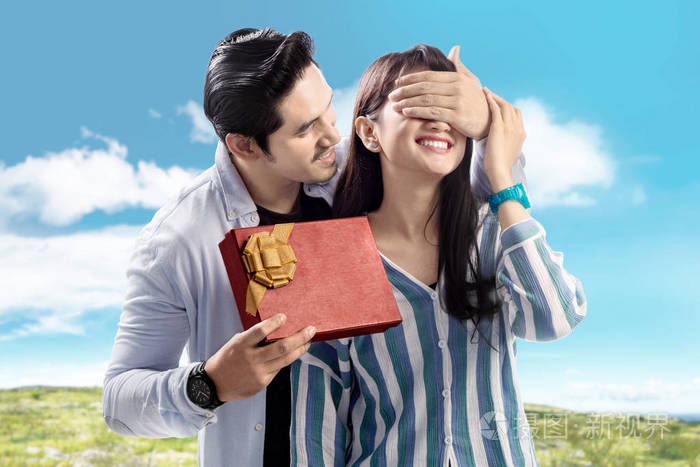 年轻的亚洲男人遮住他女朋友的眼睛给他一份礼物爱情观念和情人节