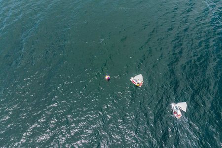 在地中海翡翠海参加赛马会比赛的小型帆船上的青少年的空中无人机照片