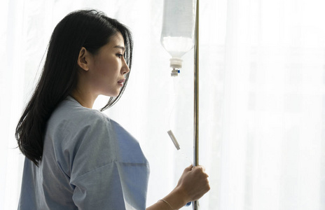 女性住院患者静脉注射生理盐水iv坐在轮椅上与亚洲妈妈住院的年轻女性