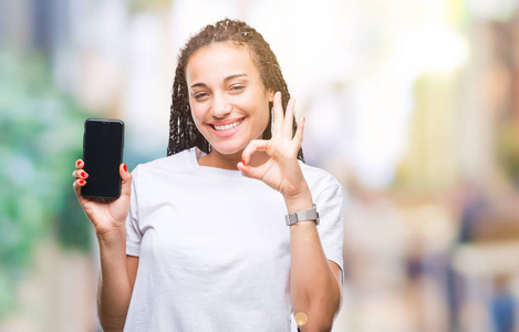 年轻的发非洲裔美国女孩显示智能手机屏幕在孤立的背景下，用手指做OK标志，优秀的符号