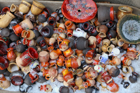 破碎的小陶瓷水壶和杯子躺在雪地下的一个村庄垃圾场上.