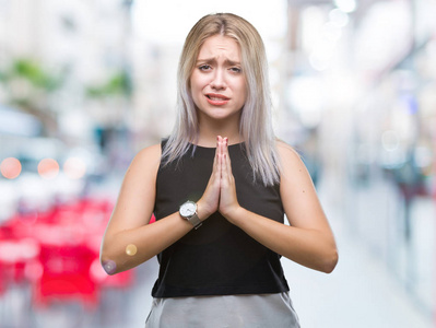 年轻的金发女人在孤立的背景下乞讨和祈祷，双手和希望的表情在脸上非常情绪化和担心。请求原谅。宗教观念。