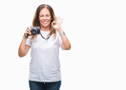 中年西班牙裔妇女用老式的照片相机在孤立的背景下拍照，用手指做好标记，非常好的象征