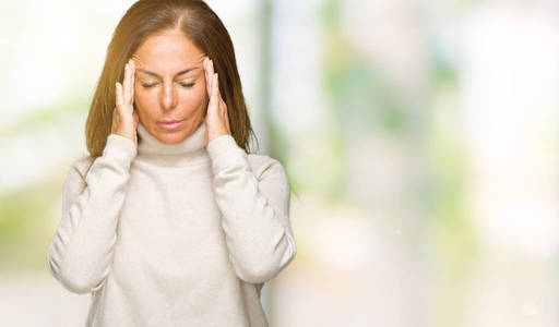 美丽的中年妇女穿着冬季毛衣，在孤立的背景上，手在头上疼痛，因为压力。偏头痛。