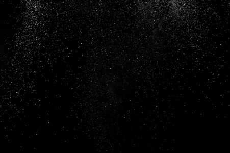 白色粒子在黑色背景上的冻结运动. 粉末爆炸. 抽象灰尘覆盖纹理.照片