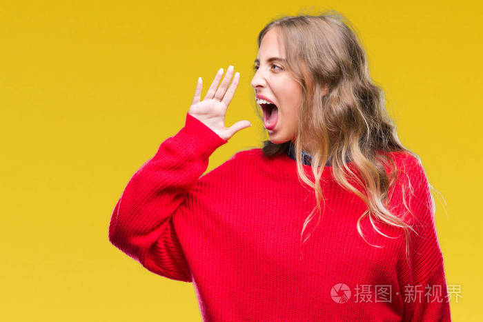 美丽的年轻金发女子穿着冬季毛衣,在孤立的背景上大声喊叫,并大声尖叫