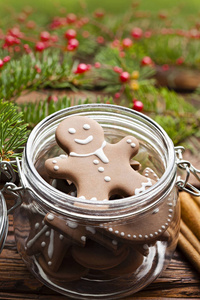 姜饼圣诞饼干放在罐子里肉桂榛子和木桌上的云杉树枝上