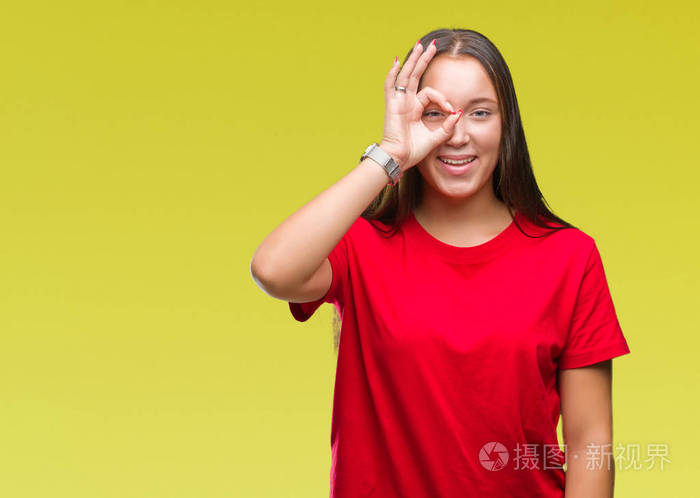 年轻美丽的白种人女人在孤立的背景下做ok手势,用手微笑的眼睛透过