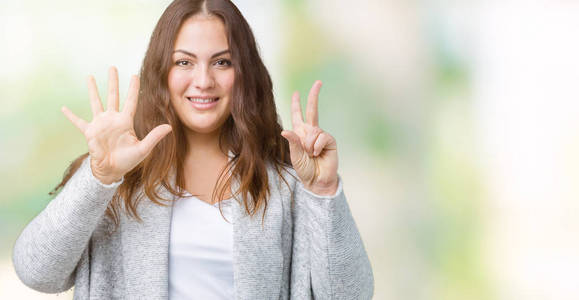 美丽的加上大小的年轻女子穿着冬季夹克，在孤立的背景上，显示和指向7号手指，同时微笑自信和快乐。