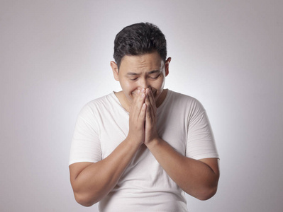 年轻的亚洲男人的肖像,穿着休闲的白色衬衫,用手指捂住脸哭泣.