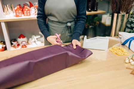 女卖家用剪刀礼品盒装饰剪包装纸。 女人包在桌子上装饰程序