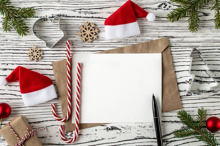 圣诞邮件，放在圣诞树枝旁的轻木桌上的信件信封，圆锥体和传统的圣诞糖果。寒假概念。俯视图