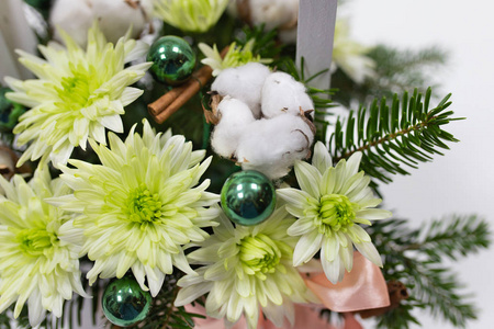 花的排列菊花浅绿色冷杉圣诞装饰品的枝条绿色棉花花和白色木箱中的粉红色丝带